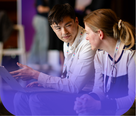 Two attendees collaborating over a laptop